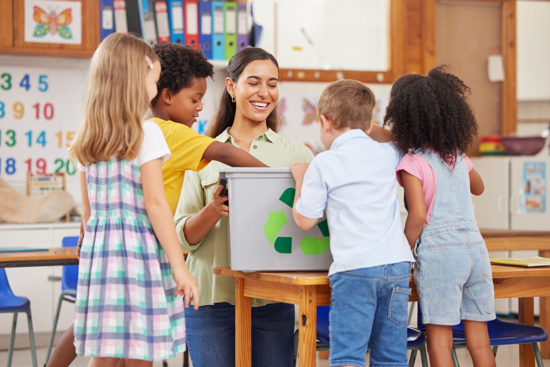 Shot of a young woman teaching  preschool children about recycling